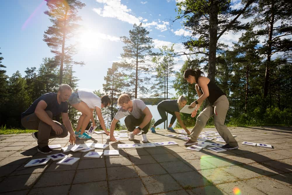 Full,Length,Of,Coworkers,Solving,Crossword,Puzzle,In,Forest